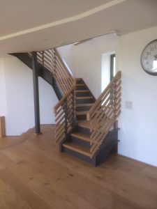 Custom Metal and Wood Staircase Extends into a Wood Floored RoomDesigned by MJ Patch Engineering team